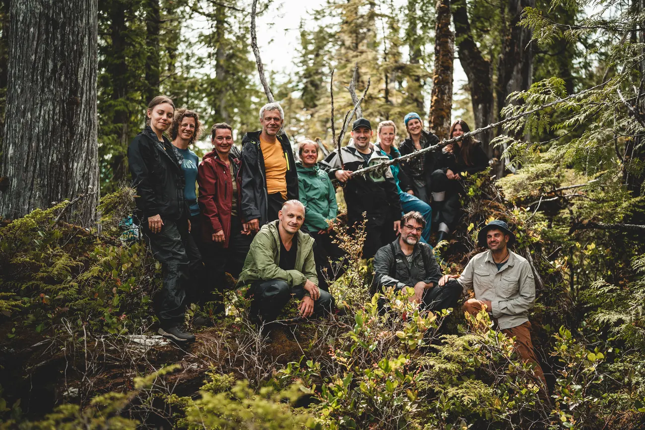 Gruppe von Menschen zwischen Bäumen im dichten Küstenregenwald auf Porcher Island